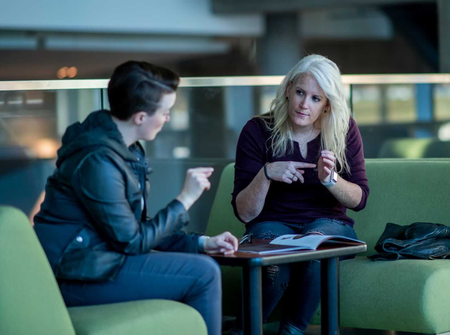 Two women have a conversation using sign language discussing a magazine article.