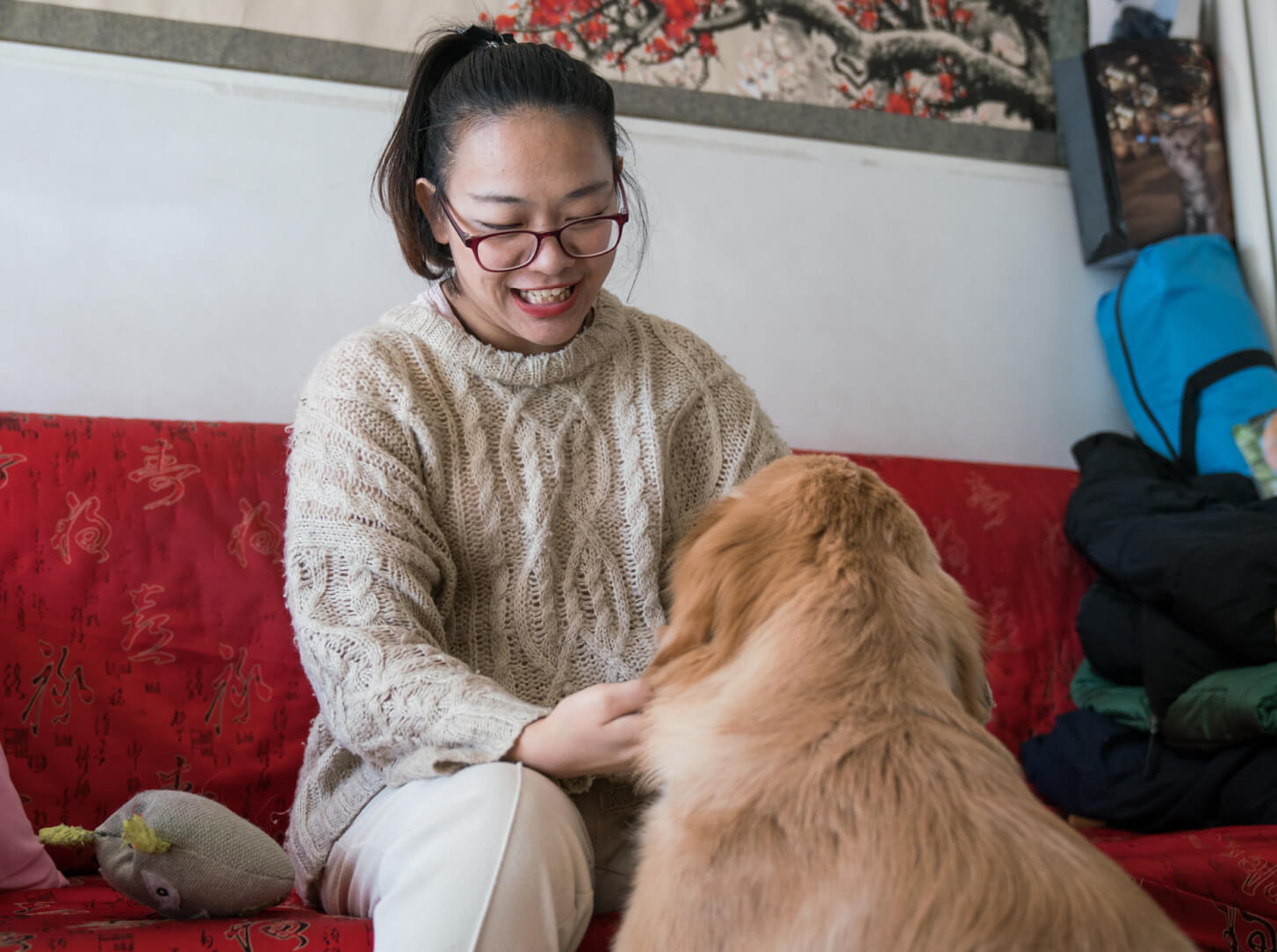 A woman is seated on a couch petting an off-duty guide dog